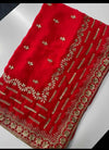 A bright red fabric textile with ornate gold floral and geometric embroidery, laid flat on a light surface.